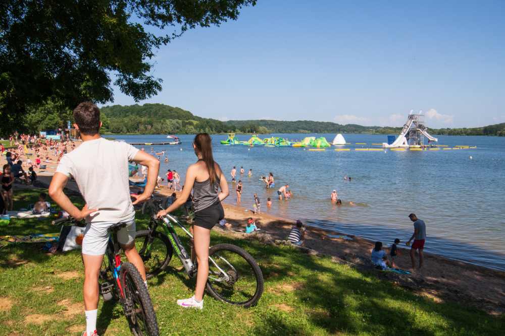 Le lac de la Liez, dans l’agglomération de Langres. Une plage avec des gens qui se baignent et des randonneurs à vélo, pendant l'été.